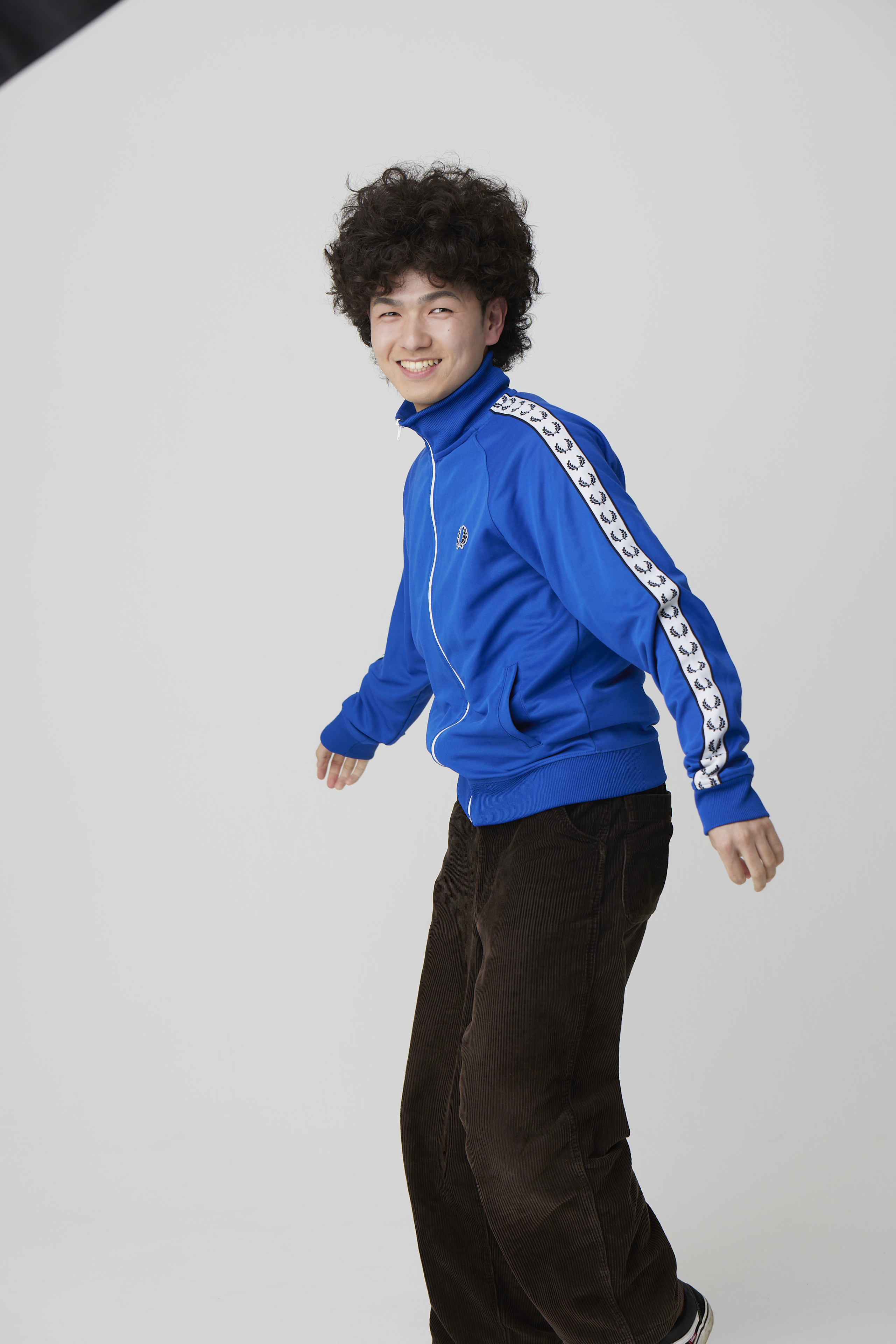 青いジャケットで笑顔を見せる新門岳大の俳優写真